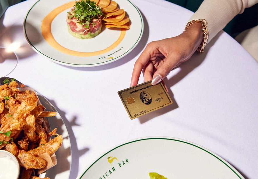 An American Express card is presented by an American Express® Card Member at a restaurant.